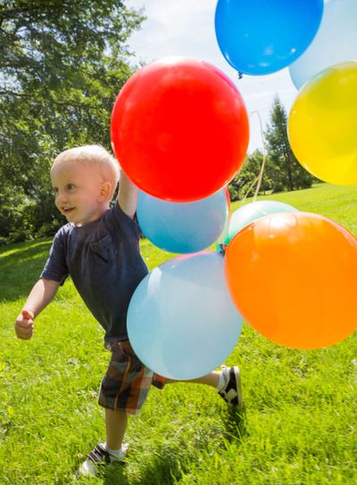 Happy Boy With Balloons Walking In Park