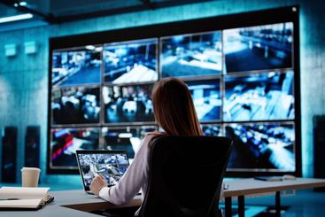 Young businesswoman examining CCTV camera footage on laptop