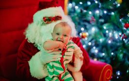 Child and Santa Claus sitting near glowing fir tree
