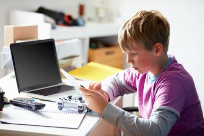 Boy Using Digital Tablet In Bedroom