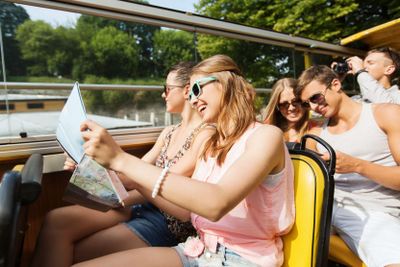 group of smiling friends traveling by tour bus