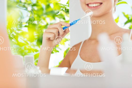 woman with toothbrush cleaning teeth at bathroom