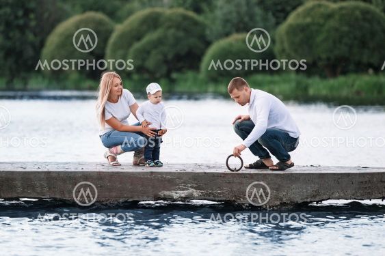 happy parents with their little son standing on the pier.
