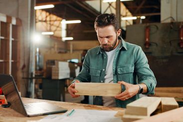 Carpenter, laptop and planning with wood to measure for...