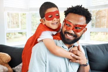 Father, child and superhero costume in home, hug son and...