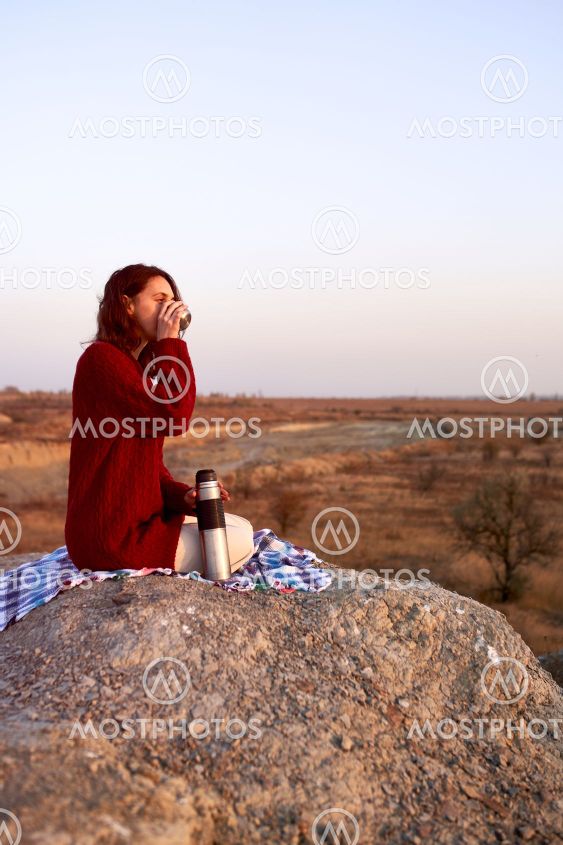 Young happy woman in red sweather relaxing, drinking...