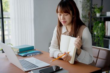Asian woman using laptop to study student engaged in...