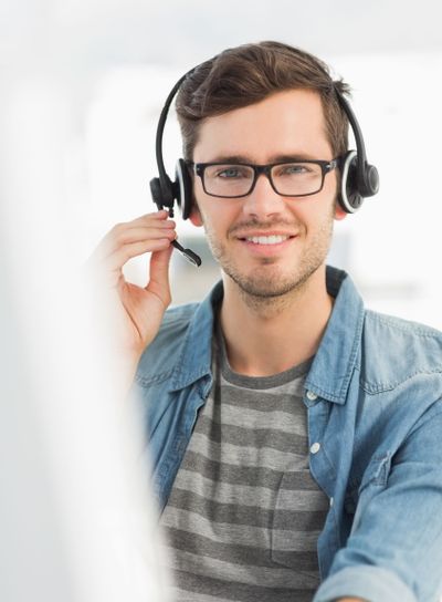 Portrait of a smiling man with headset using computer