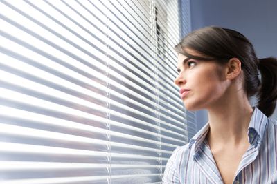Attractive woman peeking through blinds