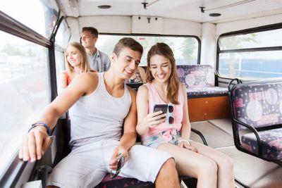 happy teenage friends traveling by bus