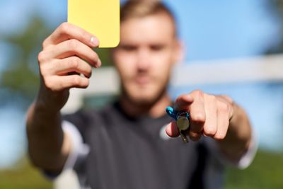 referee on football field showing yellow card