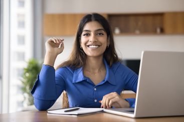 Portrait of woman sit at desk with laptop and notebook