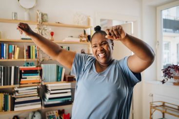 Portrait of cheerful woman dancing in living room at home