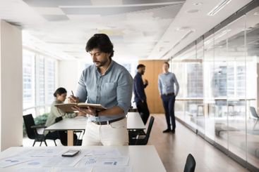 Serious Indian businessman writing notes in notebook...