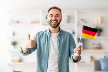 Happy Caucasian man showing thumb up and flag of...