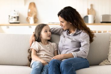 Attentive caring mother talking with little daughter...