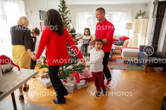Familj dansar runt granen
