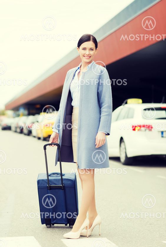 smiling young woman with travel bag over taxi