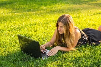 Attractive teenager girl having fun with laptop outdoors