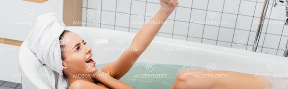 Cheerful woman with towel on head lying in bathtub, banner