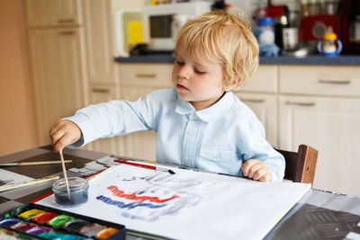 Adorable boy of two years drawing with paints.