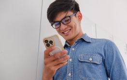 Smiling young man using a smartphone in a modern office