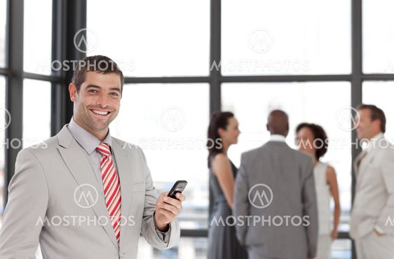 Hispanic businessman holding a phone at workplace with his colleagues