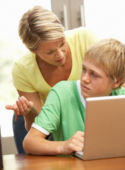 Angry Mother And Teenage Son Using Laptop At Home