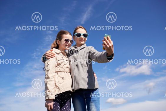 happy girls with smartphone taking selfie outdoors