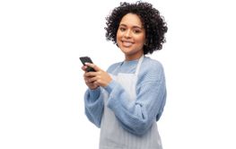 smiling woman in apron with smartphone