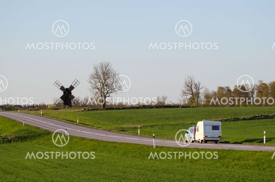 Car with caravan in a green landscape