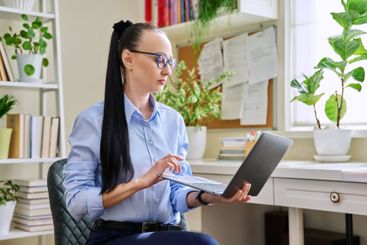 Middle-aged business confident woman using laptop on home