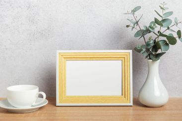 Empty photo frame, coffee cup and eucalyptus branches on...