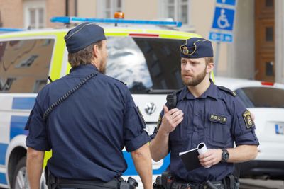 Two Swedish male police officers discussing in front of a...