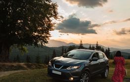 Woman goes to the car. Sunset in the mountains