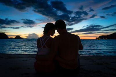 Young couple kissing on a dreamy beach at dusk during...