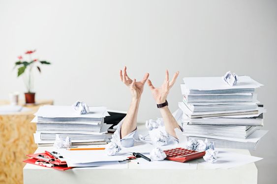 The many crumpled papers on desk of stressed male workplace