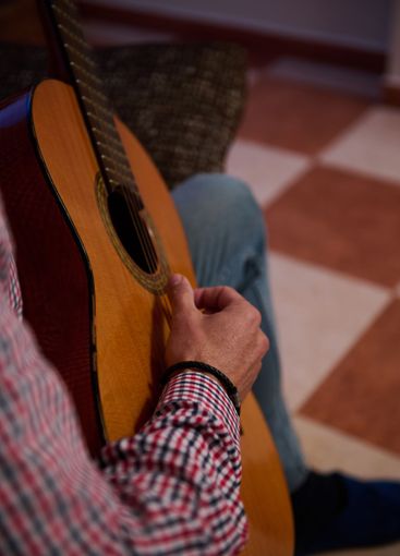 Close-up of a person strumming a guitar indoors