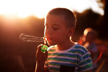 Bubbles, blowing and child in park with fun, sunset...