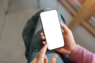 A close-up top view of a woman in jeans sitting indoors...
