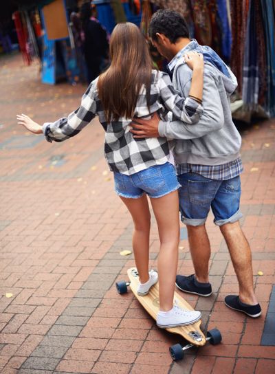 Couple, skateboarding and teaching in city, back and...