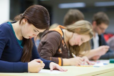 pretty female college student sitting in a classroom full...