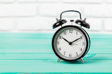 Black vintage alarm clock on wooden table