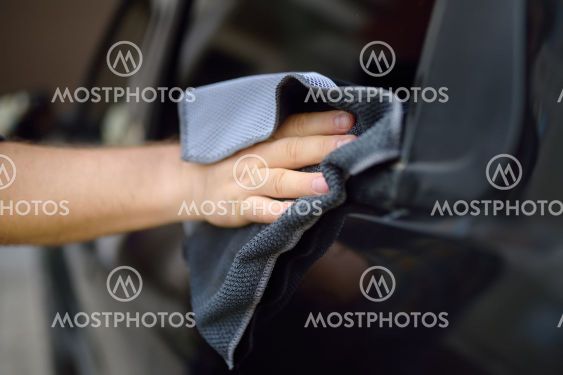 A mature man cleans his car with rag. Driver washes the...
