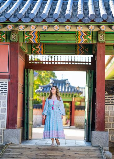 Woman in blue dress standing at Korean temple entrance