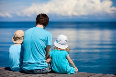 Father and kids sitting on wooden dock