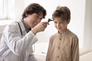 Smiling male doctor use otoscope to examine child...