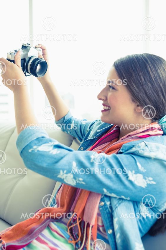 Smiling brunette sitting on sofa taking a selfie