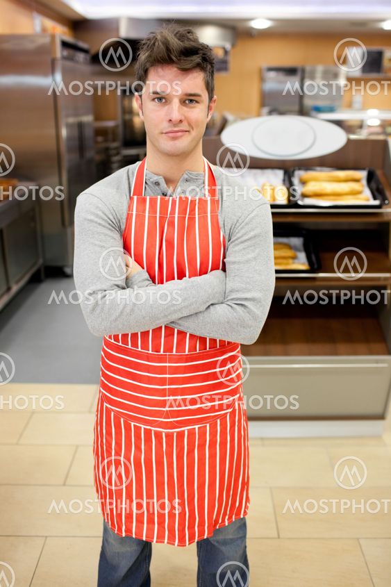 Confident cook smiling at the camera in front of his bakery