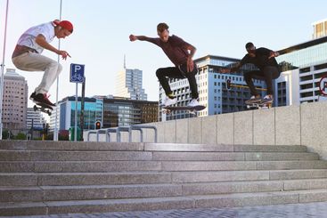 Friends, skateboard group and stunt jump in street, city...